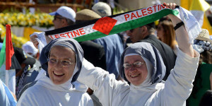 (RNS1-may11) A nun holds up a scarf that reads 'PALESTINE' before Pope Francis celebrates Mass in Manger Square outside the Church of the Nativity in Bethlehem, West Bank, on May 25, 2014. For use with RNS-PALESTINE-SAINTS, transmitted on May 11, 2015, Photo by Debbie Hill, courtesy of Catholic News Service.